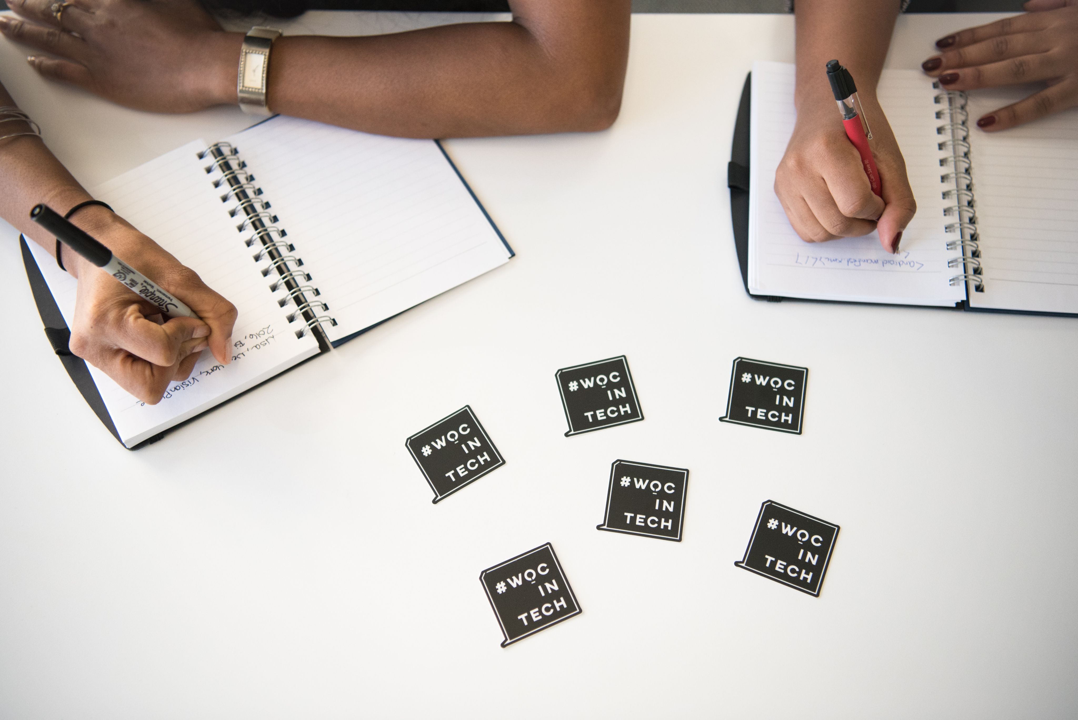 two people writing on notebooks